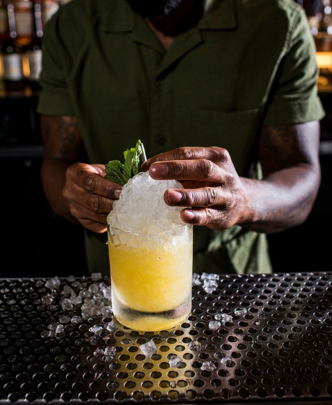 Bartender packing crushed ice into a glass mid-service.