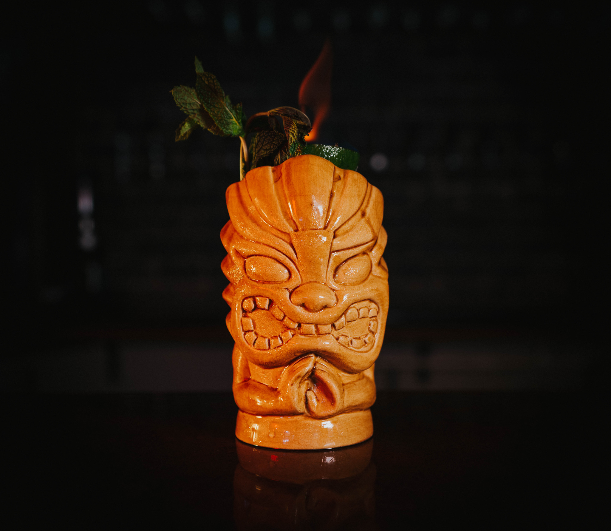 Carved tiki mug cocktail served flaming tableside.