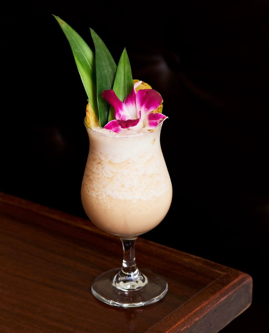 Tropical cocktail garnished with an orchid and pineapple wedge.